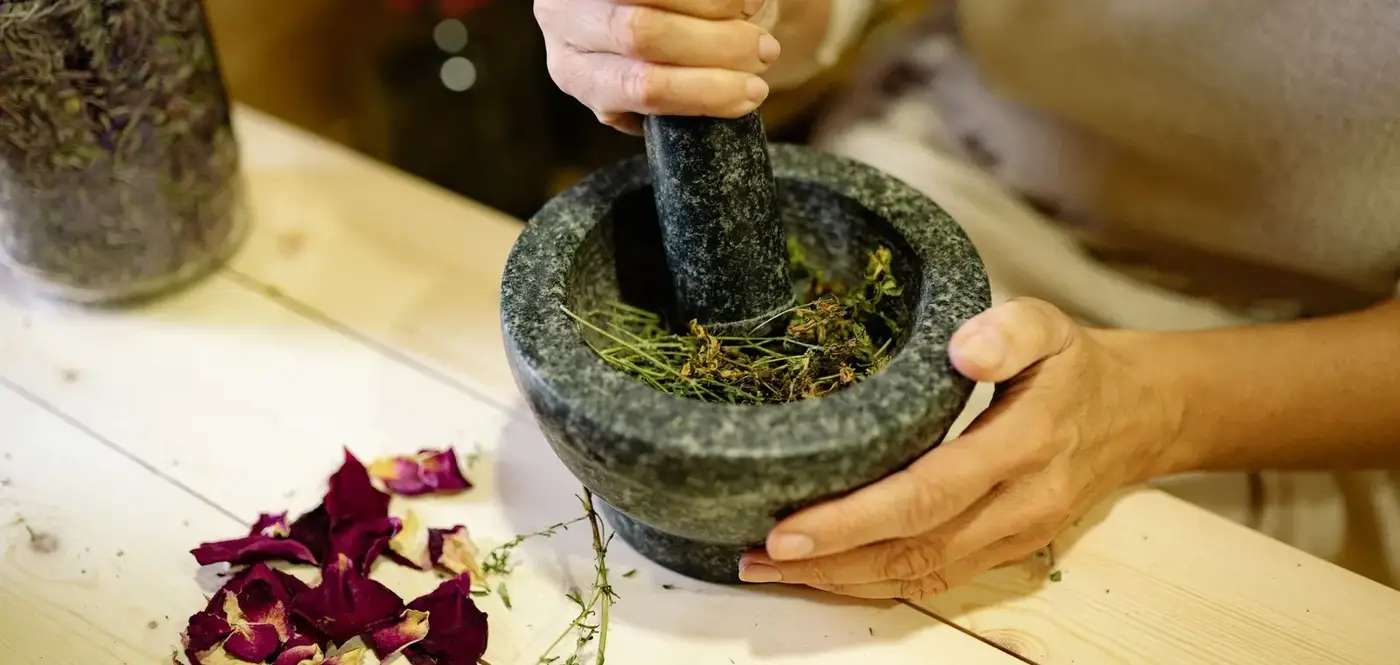 Mains broyant des herbes séchées dans un mortier de pierre